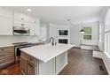 Open-concept kitchen with island flows into living area, complete with a cozy fireplace at 877 Rosalind Pl, Carmel, IN 46032