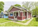 Attractive one-story home with a cozy front porch, red facade, and a neatly landscaped front yard at 1049 N Tremont N St, Indianapolis, IN 46222