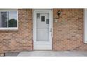 Close up of a brick front porch with a white front door with a storm door and exterior lights at 1116 Heatherwood Dr, Indianapolis, IN 46241