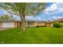 Charming brick home with a lovely front yard and an inviting covered porch with white seating at 1324 Chesterfield Dr, Anderson, IN 46012