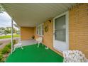 Inviting front porch with charming white seating, a decorative wreath and brick facade at 1324 Chesterfield Dr, Anderson, IN 46012