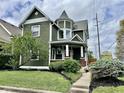 Charming two-story home with dark green siding, a turret design, and a well-maintained lawn at 1328 Sturm Ave, Indianapolis, IN 46202