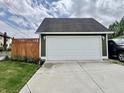 Detached garage with a large white door, situated next to a wooden privacy fence and greenery at 1328 Sturm Ave, Indianapolis, IN 46202