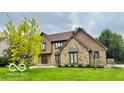 Elegant two-story home with a mix of stone and wood facade, surrounded by lush greenery and a meticulously kept lawn at 1421 Stoney Creek Cir, Carmel, IN 46032