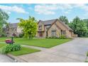Well-kept home with a stone and siding exterior, complemented by a green lawn, mature trees, and a paved driveway at 1421 Stoney Creek Cir, Carmel, IN 46032