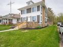 Side view of a two-story gray home with a stone chimney, featuring a well-kept lawn and landscaped front yard at 204 N Vine St, Shelbyville, IN 46176