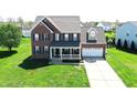 Aerial view of a two-story brick home featuring a welcoming front porch and a two-car garage at 3101 Woodhaven Way, Bargersville, IN 46106