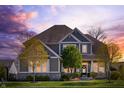 Two-story home with stone accents, gray siding, a well-kept lawn, mature trees, and a welcoming porch at sunset at 3561 Shady Lk Dr, Westfield, IN 46074
