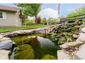 Scenic pond with a waterfall feature, landscaping, and aquatic life at 4091 W Briarwood Lake S Dr, Monrovia, IN 46157