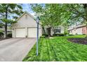 Well-maintained white brick home featuring an attached two-car garage, green lawn and mature trees at 7110 Koldyke Dr, Fishers, IN 46038