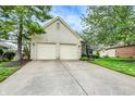 White brick home showcasing a two-car garage with lush green lawn and mature trees at 7110 Koldyke Dr, Fishers, IN 46038