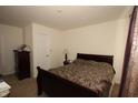 Simple bedroom with a wood-framed bed, dark dresser and carpeted floor at 7303 Beal Ln, Indianapolis, IN 46217