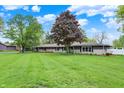 Well-maintained front lawn and lush trees frame this charming home under a sunny sky at 7425 E Thompson Rd, Indianapolis, IN 46239