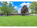 Beautiful curb appeal with lush greenery, mature trees, and a well-manicured lawn at 7425 E Thompson Rd, Indianapolis, IN 46239