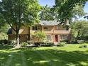 Back of home with brick and vinyl siding, a red door, and spacious yard at 7621 Forest Dr, Fishers, IN 46038