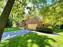 Brick home with attached two-car garage, mature trees, and lush green lawn at 7621 Forest Dr, Fishers, IN 46038