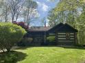 Quaint log cabin-style home with an American flag and a cozy porch surrounded by lush greenery at 7916 N Lasalle Rd, Morgantown, IN 46160