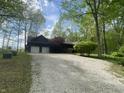 Charming log home featuring a two-car garage, gravel driveway, manicured front yard, and mature trees at 7916 N Lasalle Rd, Morgantown, IN 46160