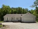 Charming one-story home featuring a two-car garage and a gravel driveway surrounded by lush trees at 8310 Goat Hollow Rd, Martinsville, IN 46151