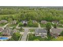 An aerial view of a residential area shows homes nestled among lush green trees at 9950 Sugarleaf Pl, Fishers, IN 46038