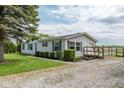 View of the house featuring clean vinyl siding, dark shuttered windows, a quaint deck, and gravel driveway at 1683 W County Road 300 S, Danville, IN 46122
