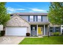 Two-story home features gray siding, a brick facade, blue shutters and a yellow front door at 1831 Brook Crossing Way, Indianapolis, IN 46229