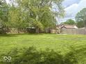 Large backyard with mature trees and a wooden fence, offering privacy at 212 Vasbinder Dr, Chesterfield, IN 46017