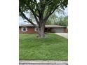 Lovely one story home with mature tree, brick facade, and a two-car garage at 2935 Flintwood Dr, Columbus, IN 47203