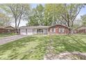 Inviting single-story brick home with attached two-car garage and a lush green lawn at 4050 Westover Dr, Indianapolis, IN 46268