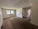 View of the living room with brown carpet, textured ceilings and two windows allowing natural light at 4109 East 21St St, Indianapolis, IN 46218