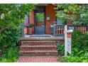Charming brick porch with brick steps, a 'For Sale' sign and lush greenery surrounding the entrance at 419 N College Ave, Indianapolis, IN 46202