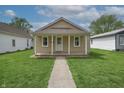 Attractive single-story home featuring a covered porch and green front lawn at 52 N Ross St, Columbus, IN 47201