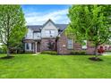 Beautiful brick home with a red door, manicured lawn, and lush landscaping at 5942 Tioga Ct, Bargersville, IN 46106