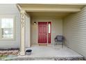 Inviting front porch with a red door, chair, and neutral siding for a cozy entrance at 7907 Oakdale Ln, Indianapolis, IN 46214