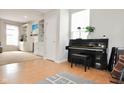 Bright living room showcasing a piano, built-in shelving, and light wood floors at 9718 Jupiter Pass, Carmel, IN 46032