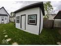 This backyard shed features white siding, a black roof, and is well-lit by windows at 1035 Albany St, Indianapolis, IN 46203