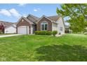 A charming home featuring lush green lawn, brick accents and mature tree at 1105 Wild Ridge Blvd, Brownsburg, IN 46112