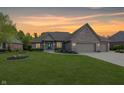 Charming brick home featuring an attached three-car garage, well-manicured lawn, and colorful garden beds at 1297 Morningside Dr, Greenfield, IN 46140