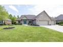 Beautifully landscaped brick home featuring an attached three car garage and a bright blue front door at 1297 Morningside Dr, Greenfield, IN 46140