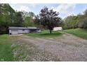 Charming gray home with gravel driveway leading to an outbuilding, all surrounded by lush greenery at 3282 S Conservation Club Rd, Morgantown, IN 46160