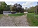 A gravel driveway splits, leading to the house and a large outbuilding against a wooded backdrop at 3282 S Conservation Club Rd, Morgantown, IN 46160