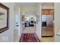 Open hallway showcasing a view into the living area with stainless steel refrigerator to the side at 3480 Limelight Ln, Whitestown, IN 46075