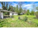 Large backyard enclosed by chain-link fence, featuring a detached garage, and mature trees at 4941 Mathews Ave, Indianapolis, IN 46227
