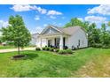 Beautifully landscaped front yard featuring a manicured lawn, decorative shrubs, and a covered porch at 5580 Pintail Ln, Greenwood, IN 46143