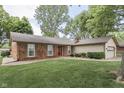 Traditional-style home features a red front door, brick facade, and well-manicured lawn and mature shade trees at 912 Ramblin Rd, Greenwood, IN 46142