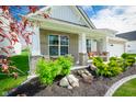 Inviting front porch with comfortable seating, beautiful landscaping, and hanging plants, creating a cozy outdoor space at 9804 Canyon Ln, Pendleton, IN 46064