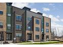 Contemporary townhome showcasing a modern brick facade with large windows, and a beautifully landscaped lawn at 9891 Baneberry Ln, Carmel, IN 46290