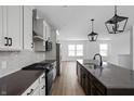 Modern kitchen features gray countertops, white cabinets, stainless steel appliances, and pendant lighting at 9891 Baneberry Ln, Carmel, IN 46290