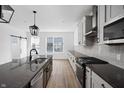 Bright, modern kitchen featuring a large island, gray countertops, pendant lighting and stainless steel appliances at 9891 Baneberry Ln, Carmel, IN 46290