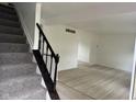 Open entryway with wood flooring and a carpeted staircase featuring a dark wood railing at 10361 E 30Th St, Indianapolis, IN 46229